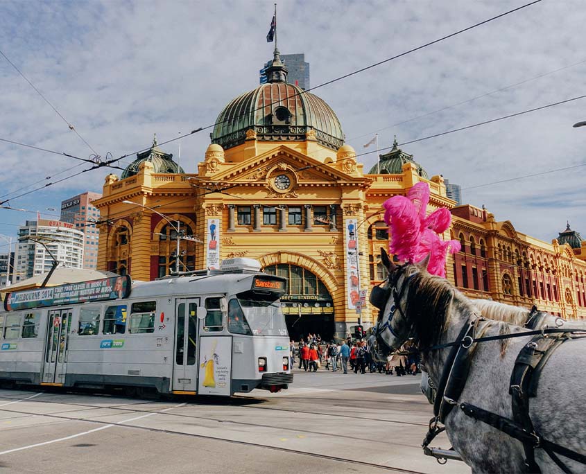 A photo of a train, horse and a building in Melbourne.