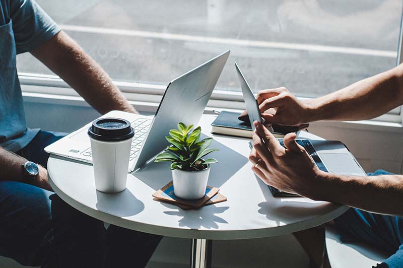 A photo of two person working on each laptops.