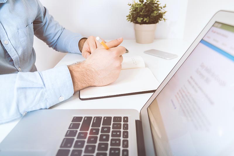 A photo of a person writing something on his note.