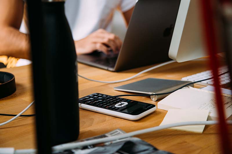 A photo of a person using a laptop and a calculator.