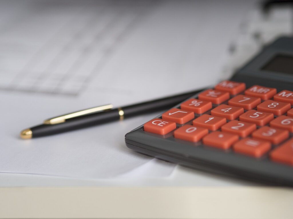 Photo of a calculator and a pen on a desk.